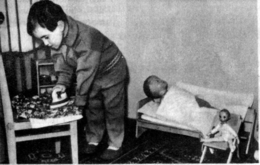 Ironing a doll’s clothes with a toy iron