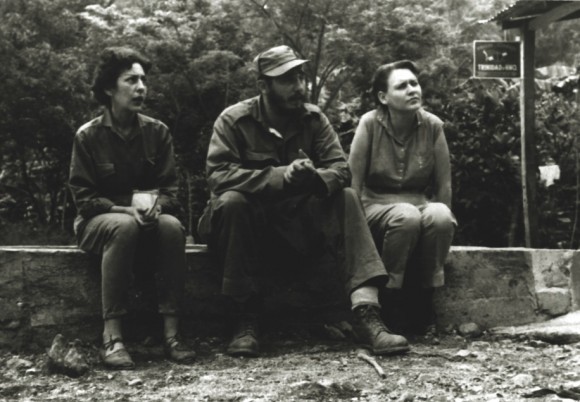Célia, Fidel e Haydée, sentados num secador de café, em abril de 1958.